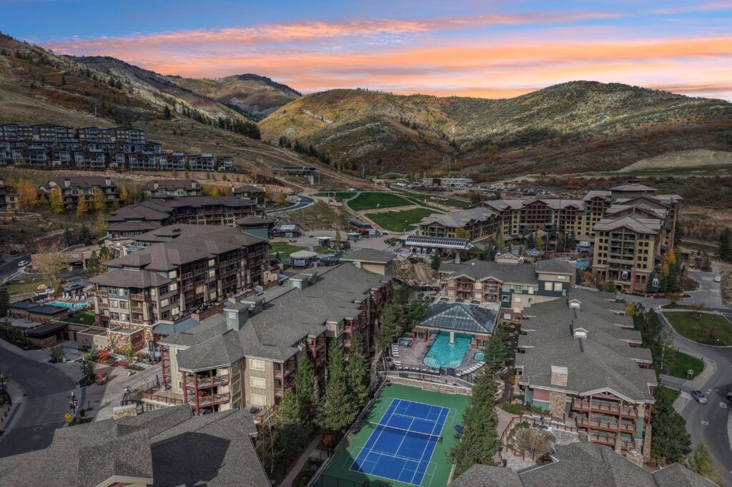 Aerial view of Westgate Park City's tennis courts and outdoor swimming pool with Canyons Village and the mountains in the background.